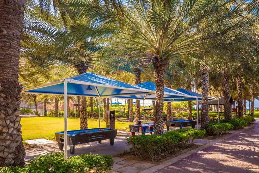 Shaded games area with pool tables among the palm trees